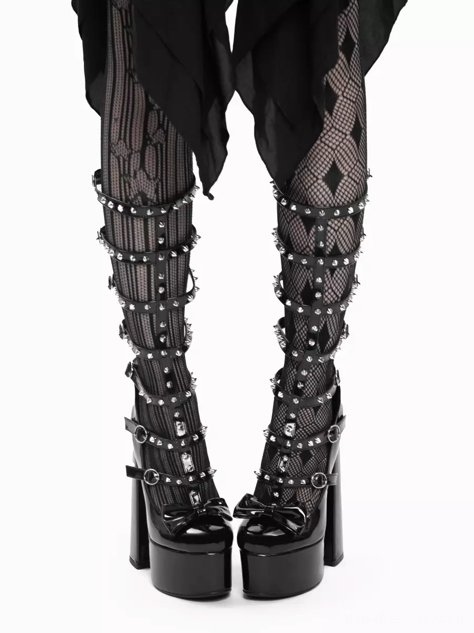 Straight-on front view of Gothic Lolita platform boots pair showing studded buckle straps, toe bow detail, chunky platform sole and matte black patent leather with striped diamond fishnet and black draped skirt