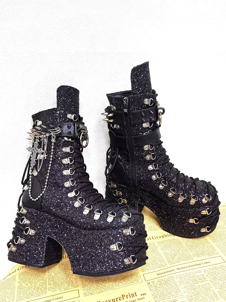 Gothic platform boots angled side view showing side zipper closure, spiked buckle strap, chain charms hanging accent, and chunky wedge platform heel detail