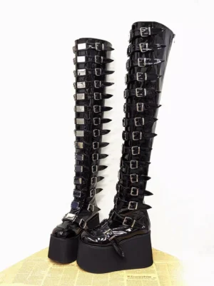 Pair of glossy black gothic lolita platform boots with multiple silver buckle straps, front flat lay view showing round toe and extensive metal grommets