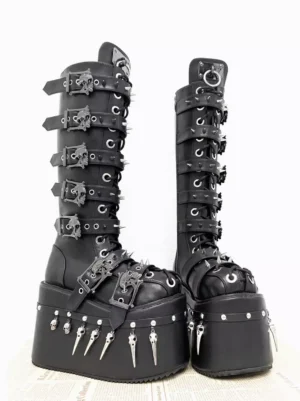 Close-up front view of gothic lolita boots highlighting metallic skull-shaped buckles and spike decorations on tall knee-high boot shaft