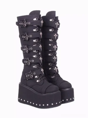 Three-quarter front view of gothic lolita knee-high boots displaying stacked metal buckles lace-up front closure studded wedge sole and black corduroy material