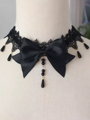 Black gothic lolita bow choker with black lace trim and black drop bead tassel worn on mannequin neck close-up front view