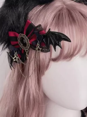 gothic lolita bow hair clip with bat wings displayed on mannequin with pink wig and black furry headwear three-quarter side view showing metal chain pendant details