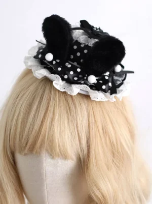 Gothic Lolita bunny ear mini hat front three-quarter view with plush black bunny ears, polka dot satin ribbon band, and white ruffled lace frills on blonde wig mannequin