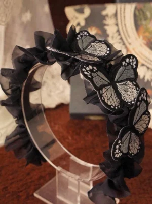 Gothic lolita ruffled butterfly hair headband with grey-black embroidered butterfly accents on black sheer ruffled band displayed on clear acrylic stand