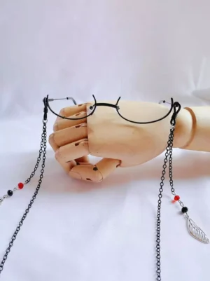 gothic lolita chain eyeglasses half-frame black metal with red black beads silver feather pendants flat lay wooden display hand