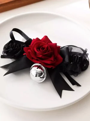 Black tulle ruffle Gothic Lolita choker necklace with red velvet rose center, silver bell charm, and black satin bows on white ceramic plate, front-facing view showcasing full design aesthetic