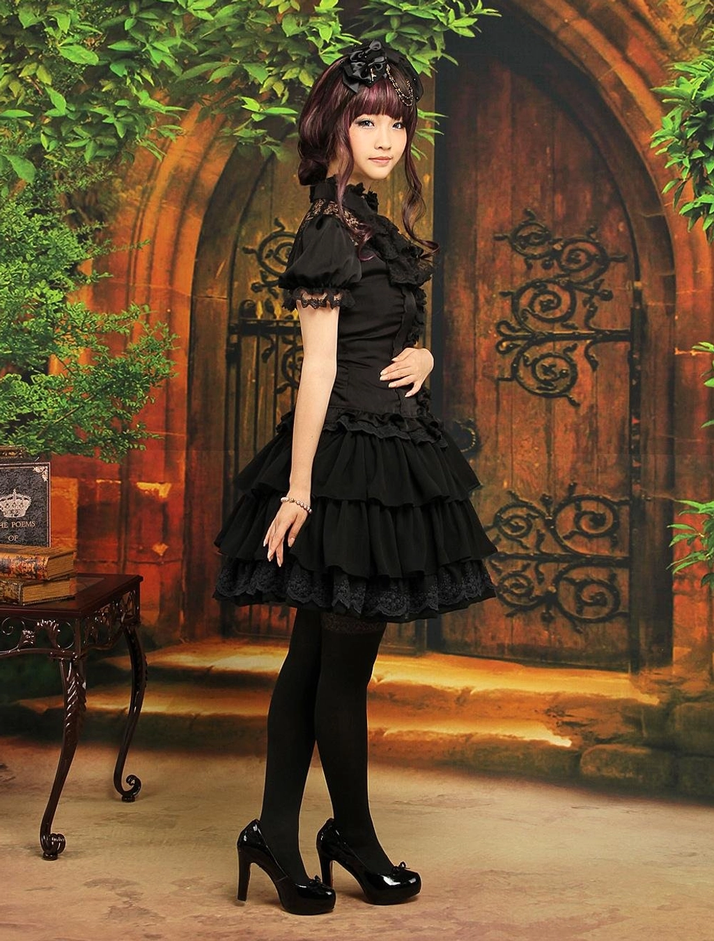 Gothic lolita fashion coordinate full body side angle showing black chiffon ruffled skirt paired with high-heeled patent leather pumps and lace blouse vintage setting