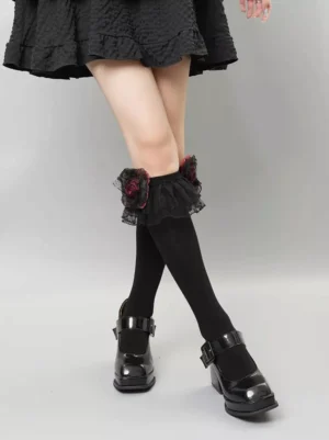Gothic lolita socks side three-quarter angle shot, black sock with wine red rose lace trim cuff, paired with black ruffled lolita skirt, demonstrating mid-calf length and cuff detail