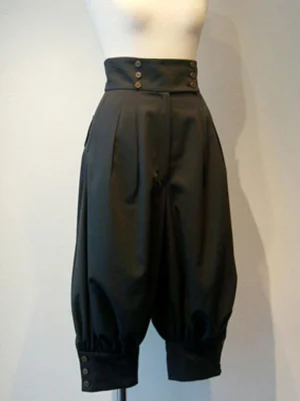 Black gothic lolita cropped pants front three-quarter view showing high waist with brass buttons, front pleats, grommet embellishments, and buttoned cropped cuffs on mannequin