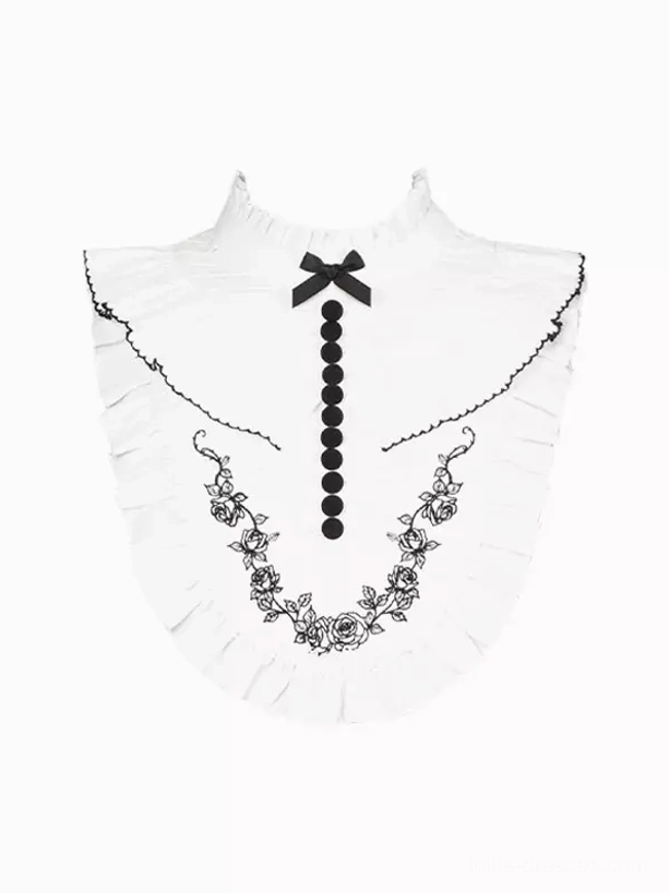 Detachable white Gothic Lolita dress collar flat lay showing floral embroidered garland pattern, black bow decoration, and button-tassel finishing details