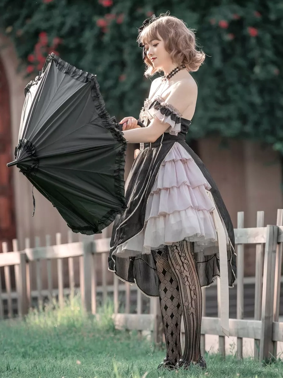 Gothic lolita dress side rear shooting view female model outdoor garden yard adjusting black umbrella layered tulle skirt patterned stockings