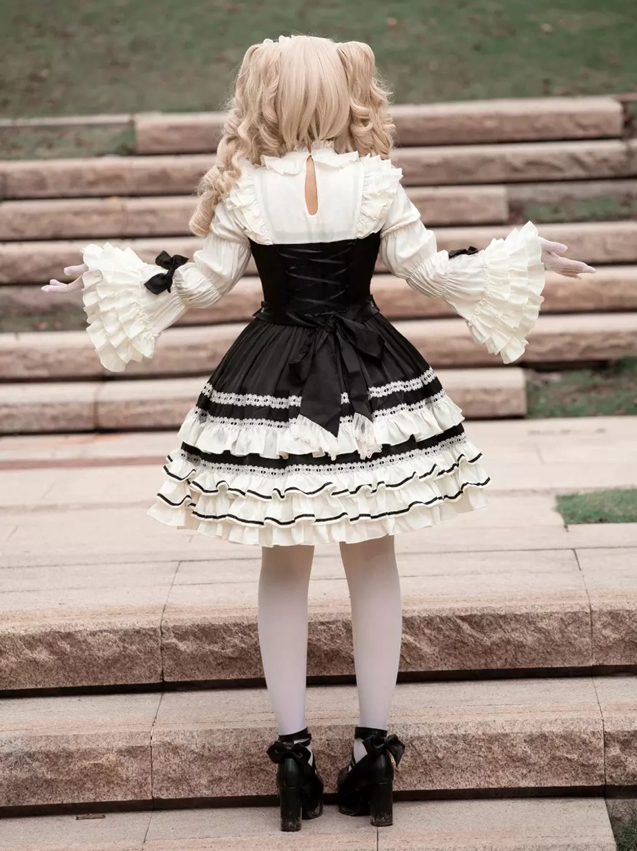 Black gothic lolita dress back full-body view with model featuring back bow embellishment, ruffled sleeves, and outstretched arms pose