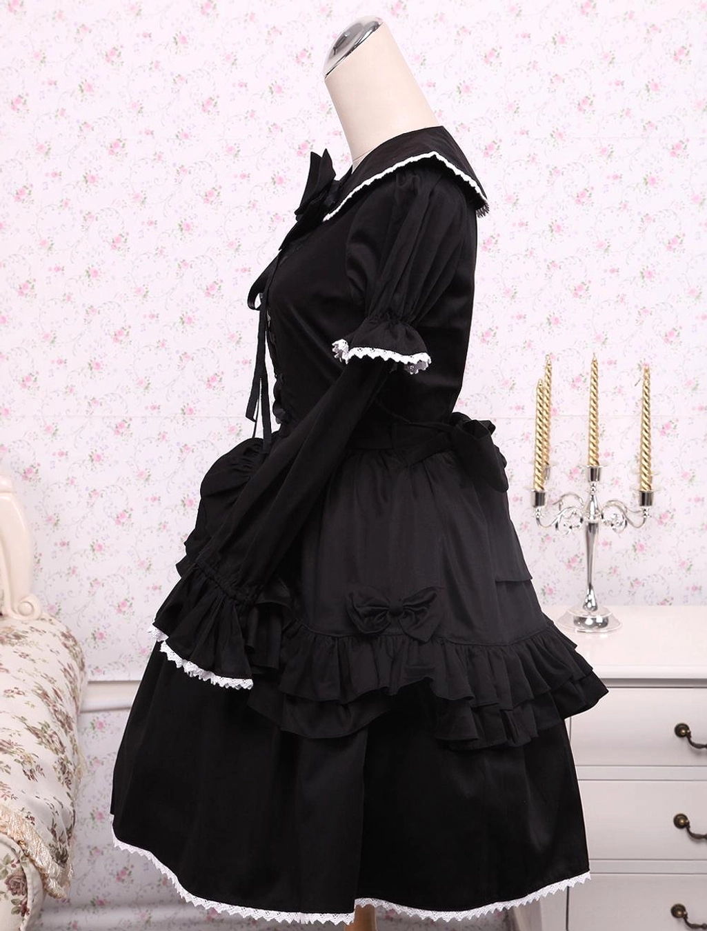 Side view of black Gothic Lolita dress showcasing side waist bow detail, tailored puffed sleeves, and multi-layered ruffled skirt silhouette