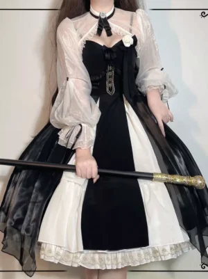Black Gothic Lolita dress front full-body view with black-white color block, sheer lantern sleeves, ruffled lace skirt hem, and decorative chest flower ornament on female model