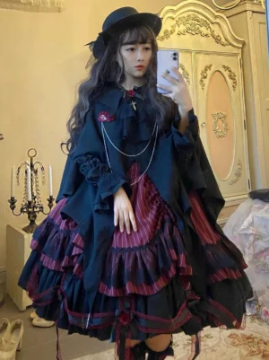 Full-body Gothic Lolita dress and cape set on model showing wine red striped ruffles rose brooch and chain decorative details