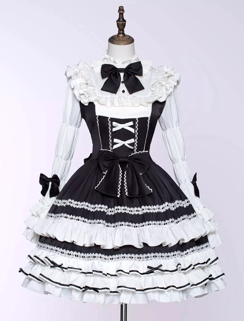Black gothic lolita dress flat lay display on dress form showing crisscross front lacing detail, lace-trimmed layered ruffled skirt, and structured design