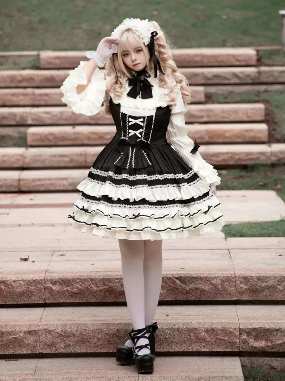 Classic black gothic lolita dress front view showing long ruffled sleeves, delicate lace trim, white stockings, and full-length silhouette on model