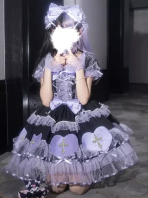 Gothic lolita dress flat lay kneeling pose showing ruffled tulle hem layered skirt and heart cross embellishments with big bow detail
