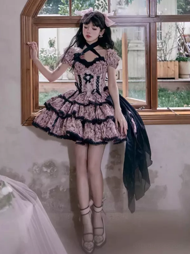 Gothic Lolita dress side profile showing layered tiered ruffles, pink head bow, trailing black sash, ankle strap heels, wooden window interior setting