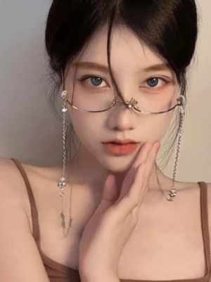 Gothic Lolita eyeglass chain with crystal pendants worn on model with half-rimless glasses, silver-toned hardware, frontal close-up view