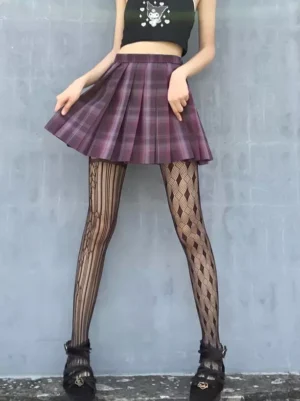 Female model wearing black fishnet pantyhose with geometric hollow pattern, purple plaid skirt, crop top, and matching platform shoes in outdoor setting
