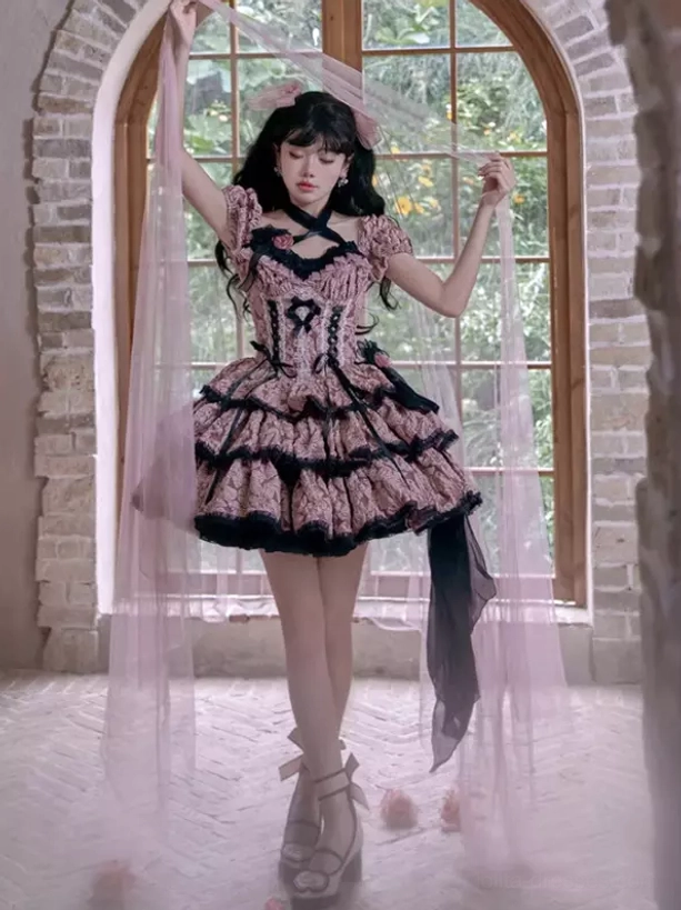 Full body front view pink and black floral Gothic Lolita dress with sheer overlay, tiered ruffled skirt, platform heels, arched brick window background