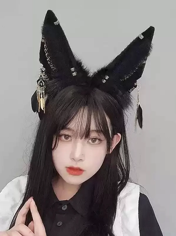 Gothic lolita black faux fur fox ear headband with rhinestones and metal feather pendants worn on live model with long black hair, front eye-level view showcasing detailed embellishments and elegant styling