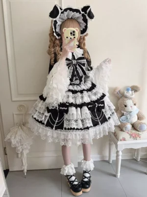 Gothic Lolita complete outfit coordinate selfie with model wearing black dress cape cat-ear headwear ruffled lace sleeves platform Mary Jane shoes brown curly twin hair indoor home background