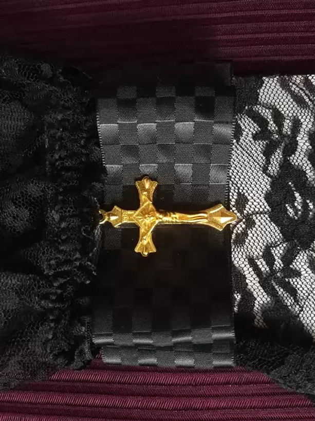 Gothic lolita glove wrist detail featuring gold cross ornament, checkered fabric strap, and ruffled black lace edge for refined oversleeve accessory styling
