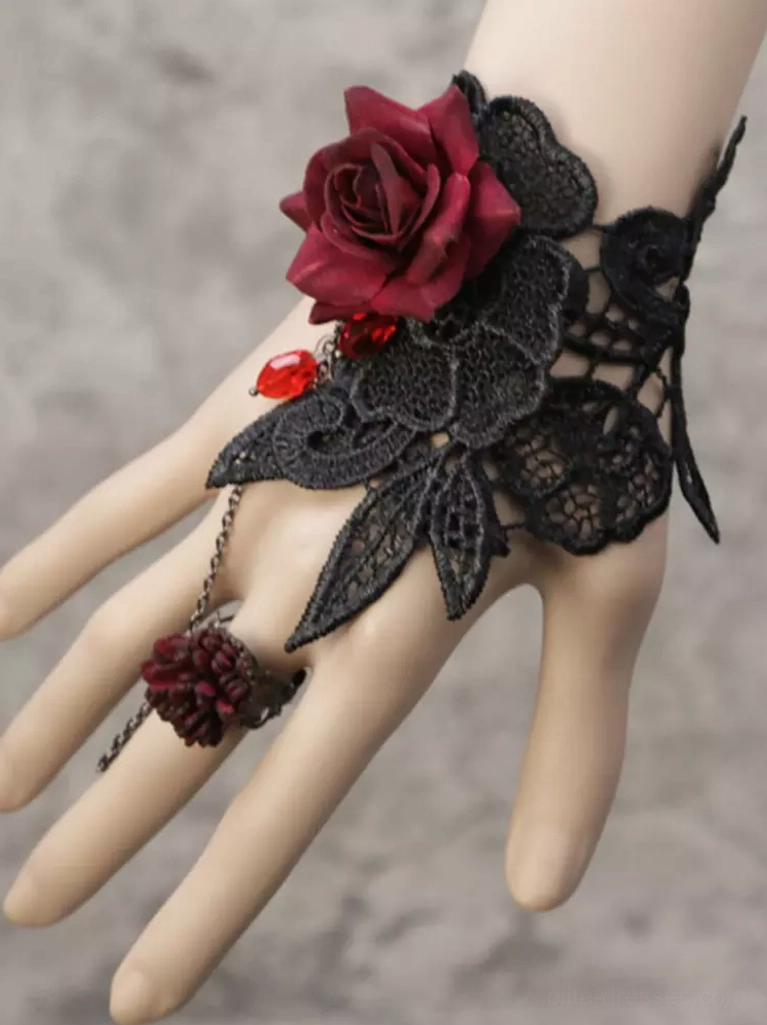 Side three-quarter view of Gothic Lolita hand chain showing black floral lace bracelet with burgundy rose focal point, red teardrop bead, and delicate chain connection to matching cluster ring on mannequin