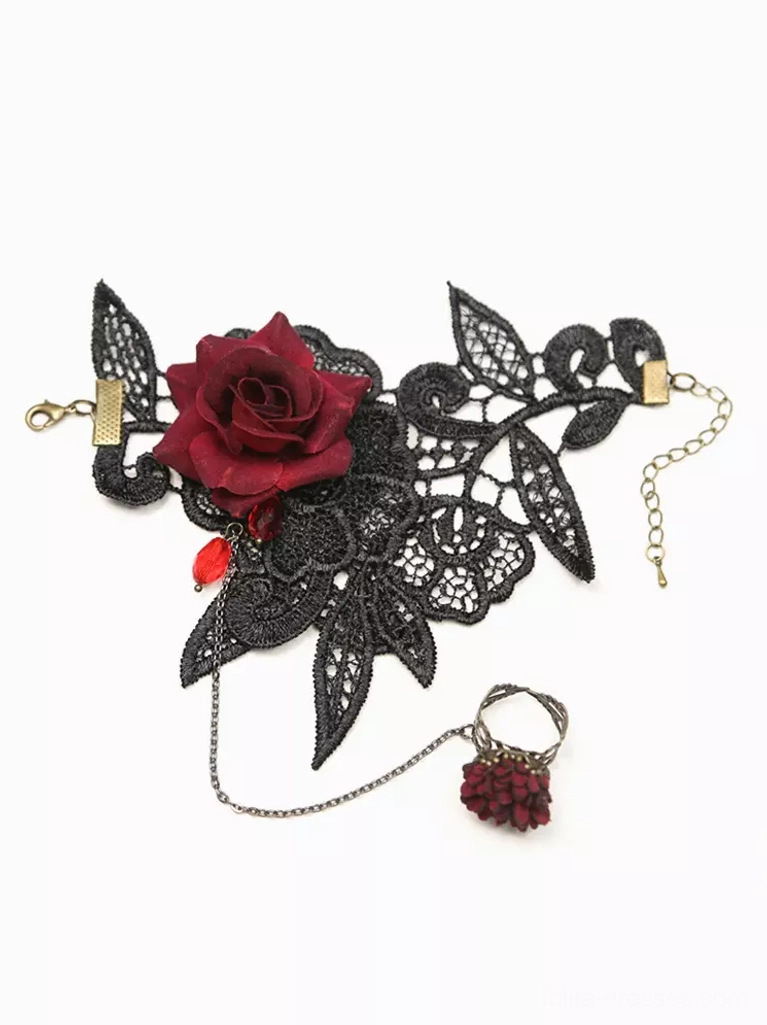 Flat lay overhead view of complete Gothic Lolita hand chain bracelet set showing black lace cuff with burgundy rose accent, red teardrop pendant, adjustable chain and matching flower ring on white background