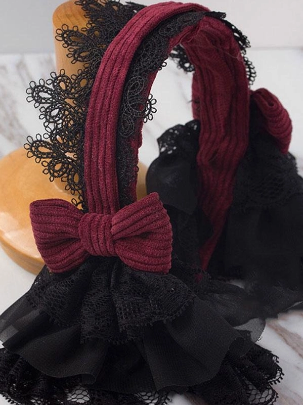 Complete Gothic Lolita headdress display on marble tabletop with display stand, overhead oblique angle showing black lace trim, layered black tulle construction, wine red corduroy bow, and full product profile from above