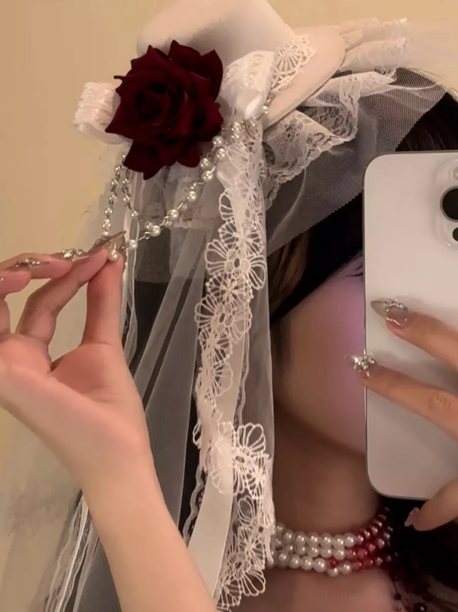 Close-up detail of Gothic Lolita headdress showing silver bead chain, red rose embellishment, white lace work, and intricate embellishments handheld shot