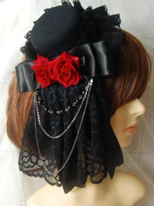Gothic Lolita mini top hat headdress featuring black lace veil with scalloped trim, crimson satin bow, and red rose decorations, displayed on mannequin with brown wig in three-quarter view