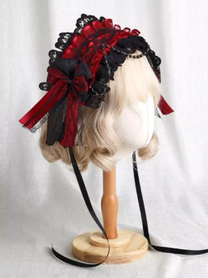 Gothic Lolita red and black lace headdress with beaded forehead trim displayed on blonde wig, showing left three-quarter angle view with side bow and flowing ribbon tails