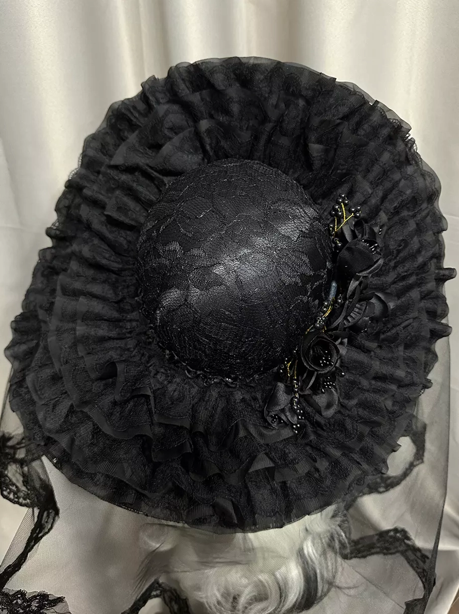 Gothic lolita wide-brimmed hat with ruffled lace brim and side black floral decorations, overhead top-down angle view