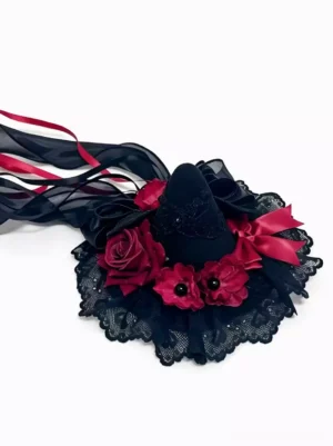 Gothic lolita witch hat hair accessory flat lay overhead view, black lace ruffled base with wine red satin roses and red bow, long flowing ribbons on white background