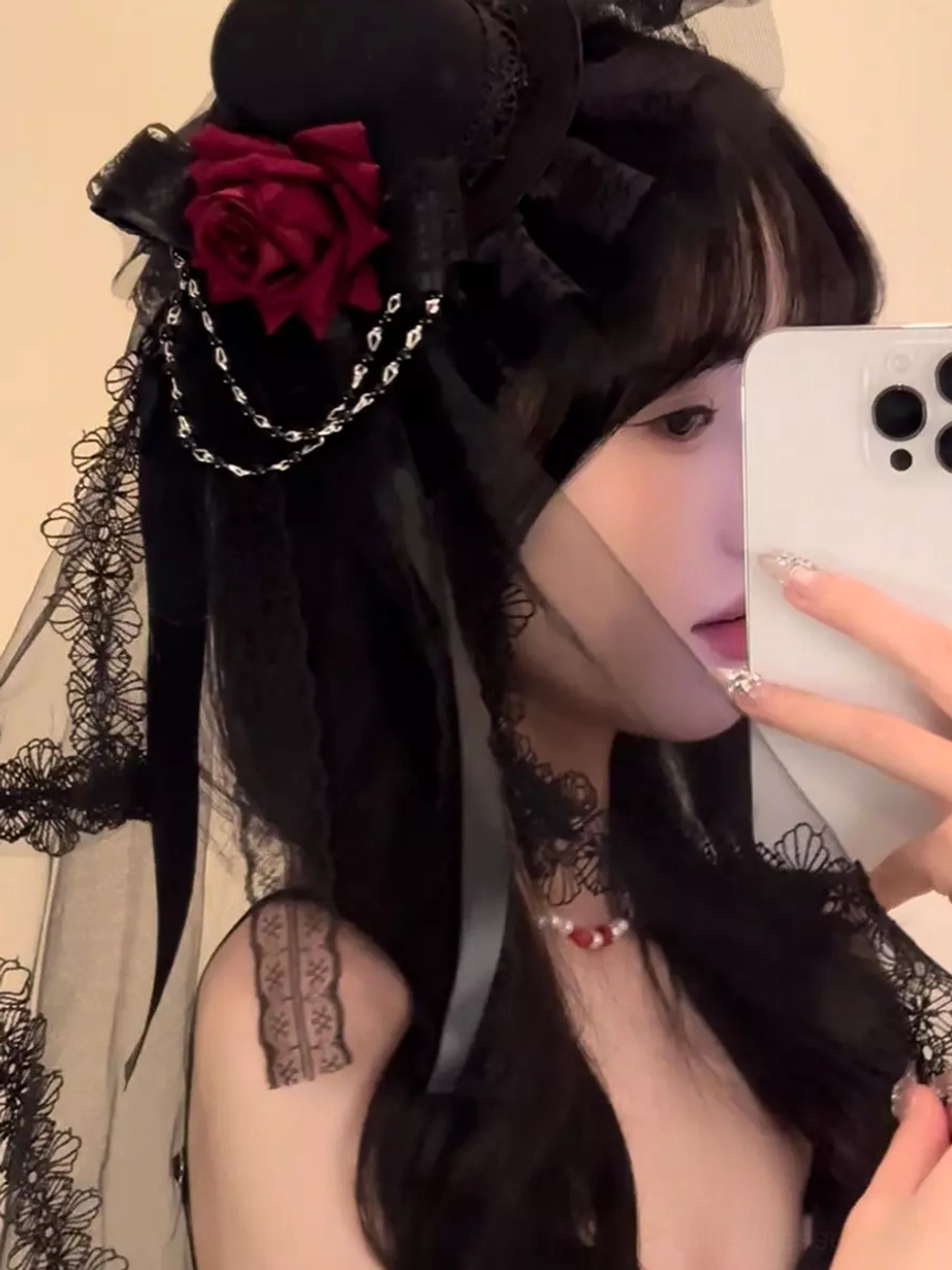 Side profile selfie perspective of Gothic Lolita headpiece featuring black ribbon, lace veil, and red rose decoration on female model with dark long hair
