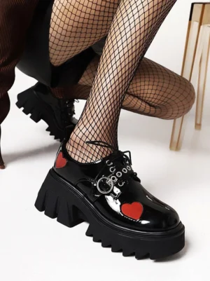 Gothic lolita heart platform loafers with glossy black PU leather and red heart patches, low angle crouching view displaying silver lace ring hardware and chunky sole detail