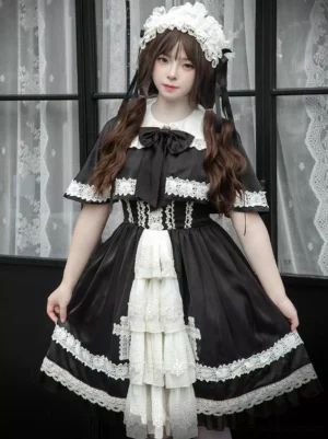 Full front view of classic gothic lolita JSK dress with layered white ruffled front panel, black skirt, cross lace appliques, Peter Pan collar with bow, and lace trim details