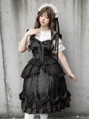 Black Gothic Lolita jumper skirt dress front angle displaying structured waist, decorative bow, and multi-layered ruffled skirt design