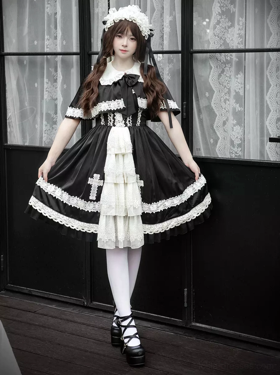 Side-front standing view of gothic lolita JSK dress showing cross embroidery on skirt, white tights, platform Mary Jane shoes, and overall proportions with lace details