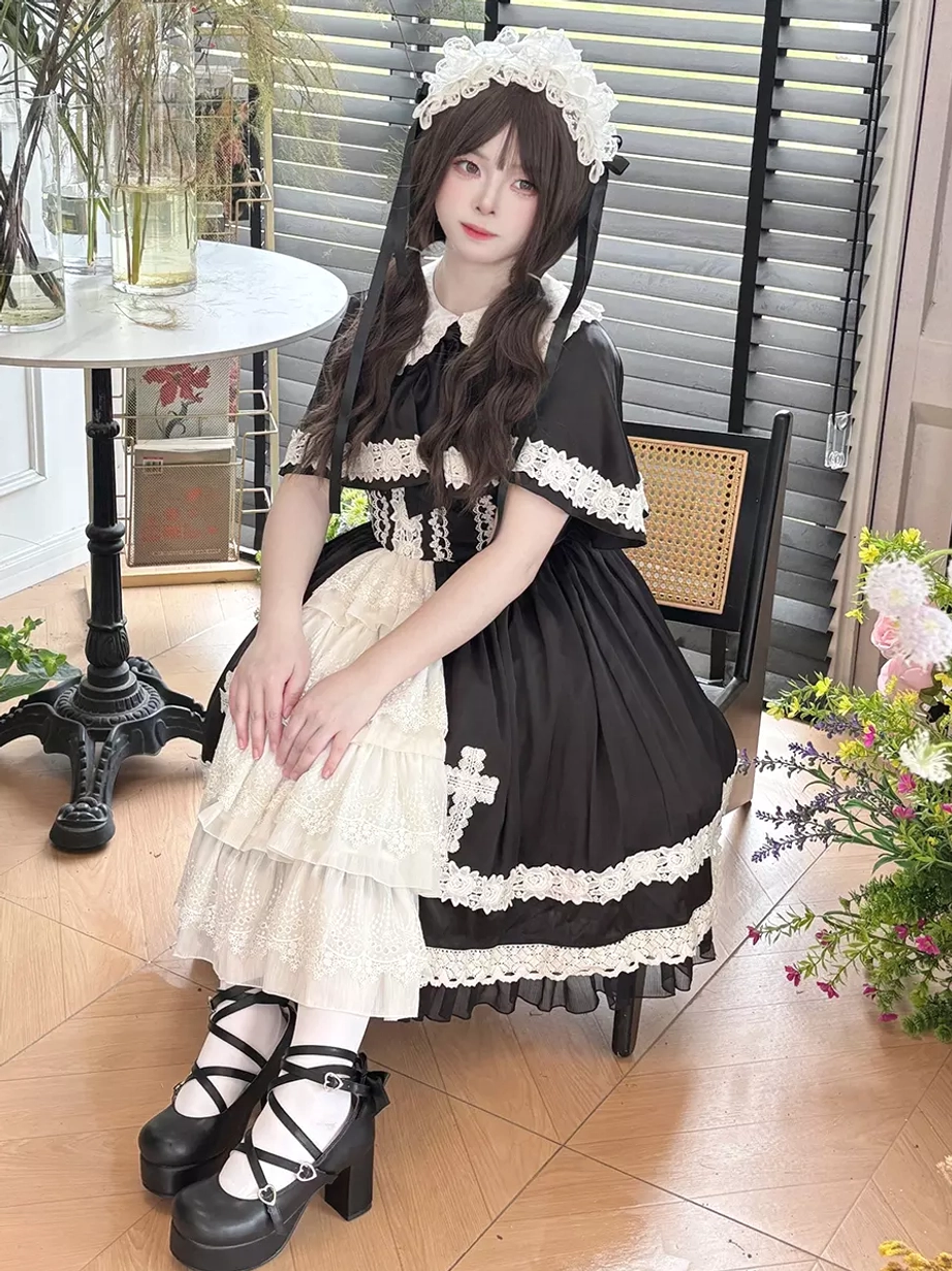 Full seated view of gothic lolita JSK dress in retro cafe setting, showing platform buckle shoes, white petticoat underneath, short lace-trimmed sleeves, and dress volume