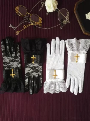 Black and white gothic lolita lace gloves with checkered wrist strap detail and gold cross ornament, styled flat lay on dark vintage fabric background for coordinate inspiration