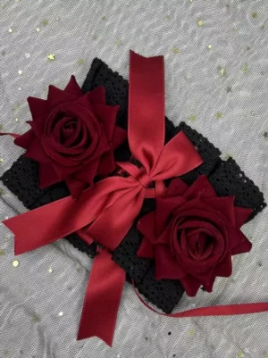 Flat lay Gothic Lolita hair accessory with black lace base two wine red roses and red satin bow on glitter tulle background