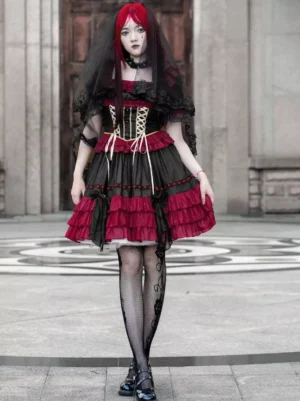 Gothic lolita lace-up corset dress with layered ruffles in black and red, front view on model with red hair wearing black gloves and lace veil