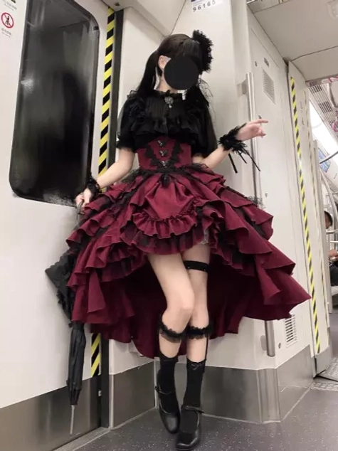 Gothic lolita outfit set front three-quarter full view in subway urban setting showing layered ruffled skirt, black leg garter, platform shoes, and short black socks styling