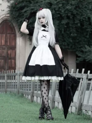 Gothic Lolita maid dress front three-quarter view on model with silver twin-tails, black and white color scheme, lace ruffle hem, short puffed sleeves, cross apron decoration, outdoor vintage aesthetic