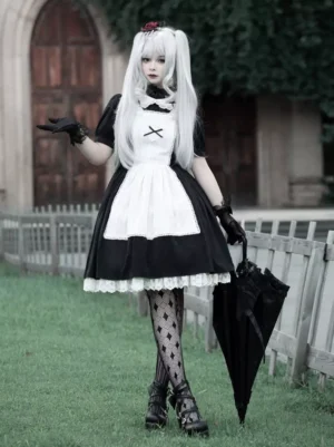 Black and white Gothic Lolita maid dress full body front view, model wearing formal black gloves, holding black umbrella, cross-patterned apron overlay, vintage architectural background